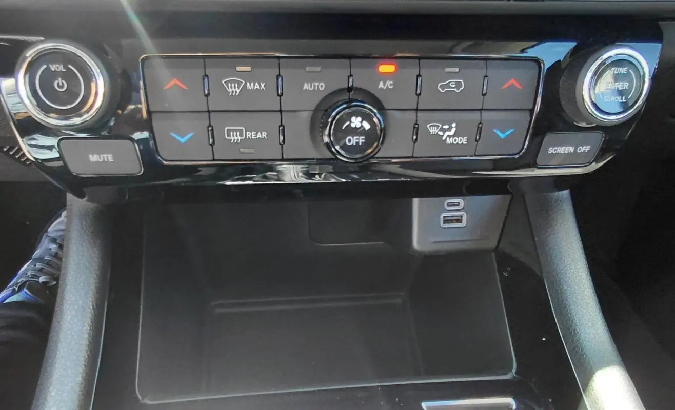Vue rapprochée de la console centrale du Jeep Compass 2025, avec commandes climatisation et ports USB visibles.