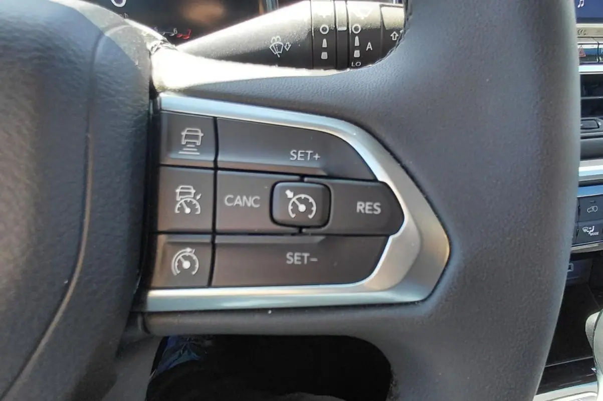 Gros plan sur les commandes du régulateur de vitesse au volant du Jeep Compass bleu 2025 e-Hybrid.