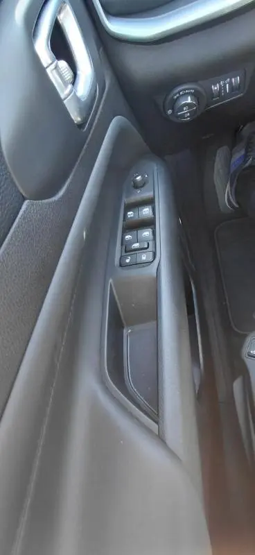 Vue rapprochée de la porte côté gauche du Jeep Compass bleu 2025, montrant les commandes électriques des vitres et des rétroviseurs.