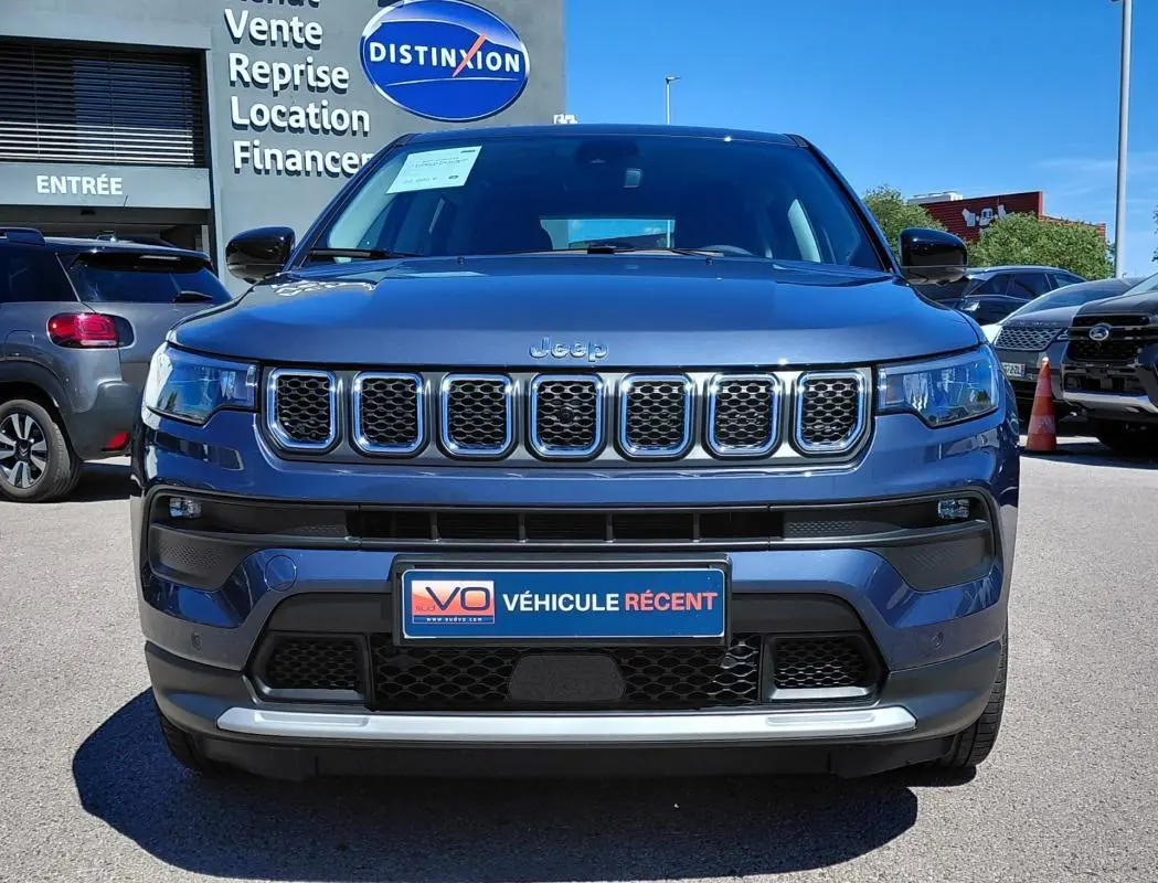 Vue frontale d'un Jeep Compass bleu 2025 avec calandre chromée et plaque "Véhicule récent" visible.
