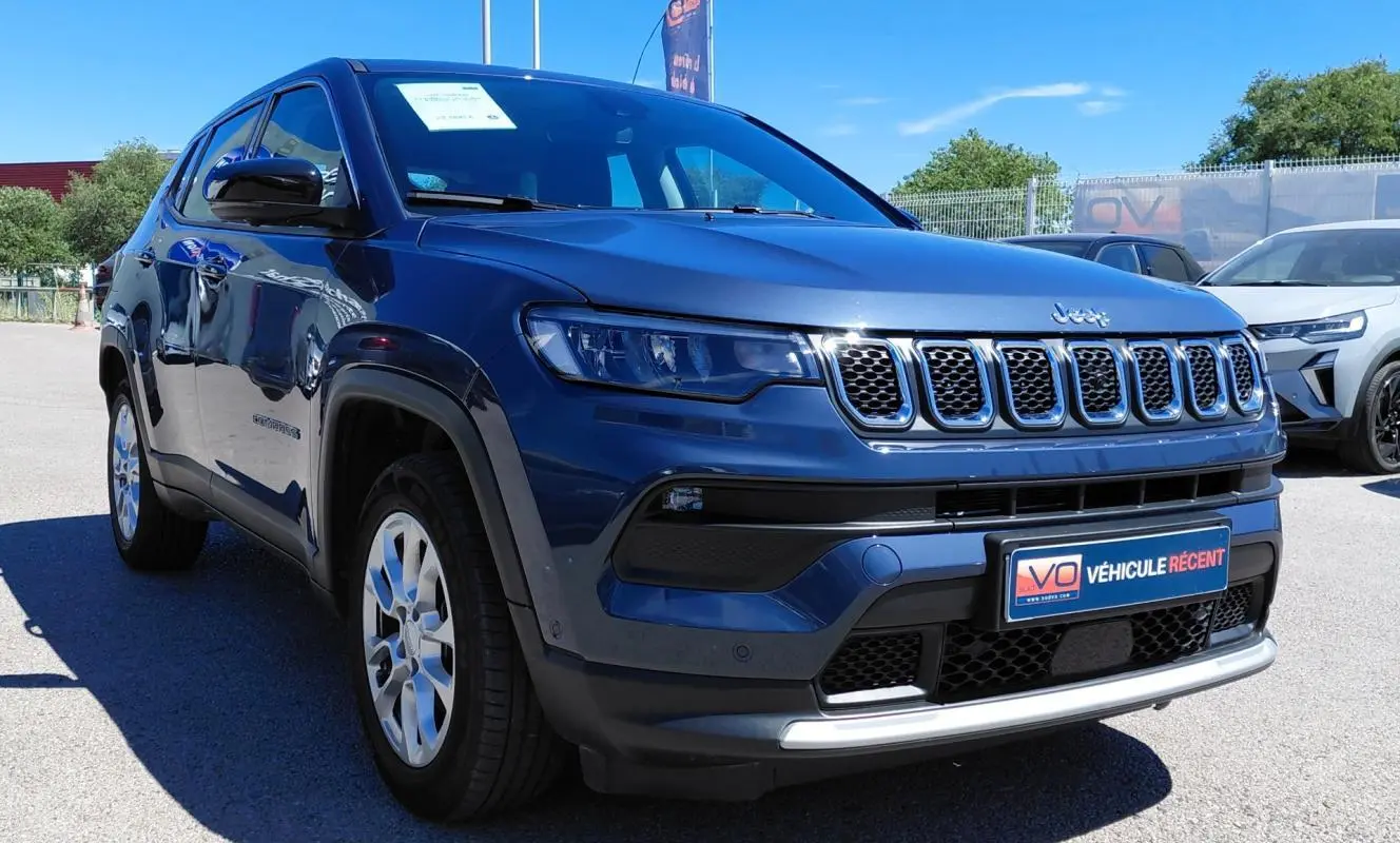 Jeep Compass bleu en 3/4 avant droit, avec calandre distinctive à sept fentes et jantes alliage 18 pouces.