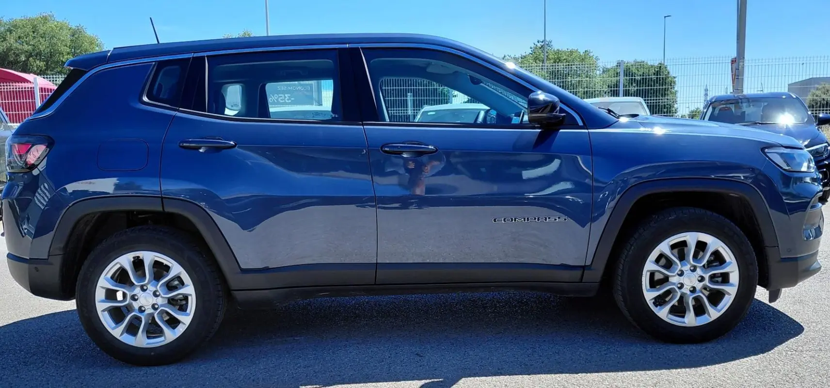 Vue latérale droite d'un Jeep Compass bleu 2025 avec jantes alliage 18 pouces et logo "Compass" sur la porte.