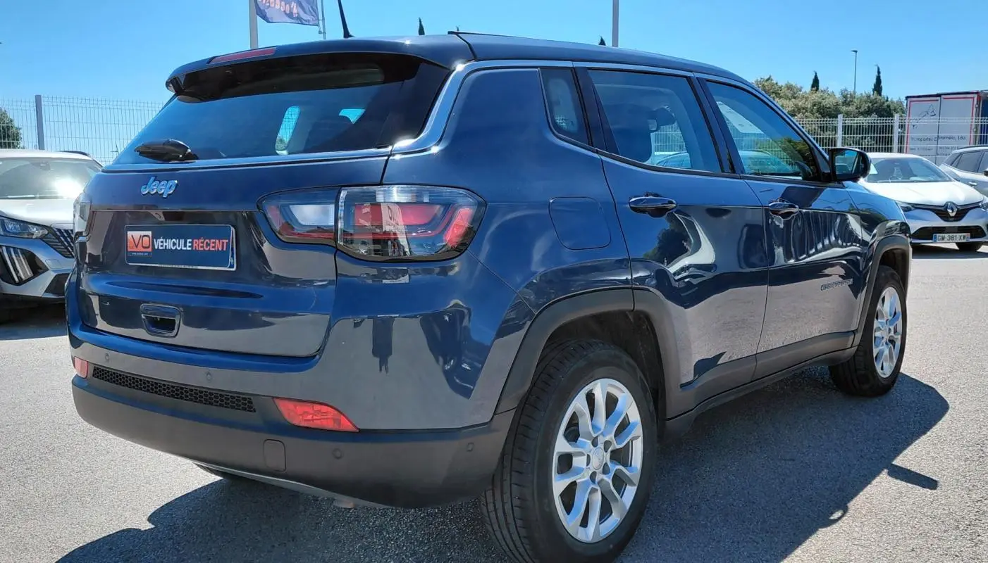 Jeep Compass bleu vue 3/4 arrière droit, avec jantes alliage 18 pouces et feux arrière LED visibles.