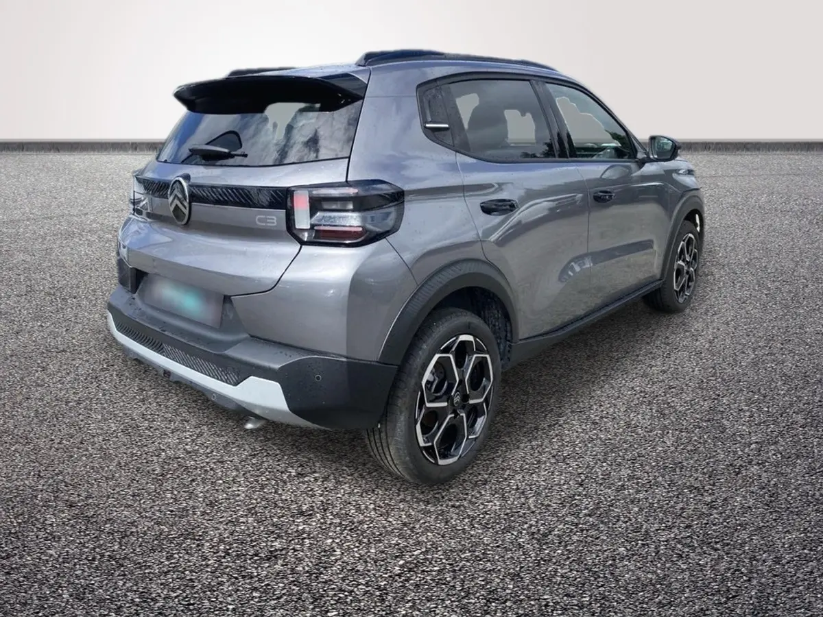 Vue 3/4 arrière droite d'une Citroën C3 hybride 2026 gris foncé avec jantes noires et détails noirs contrastants.