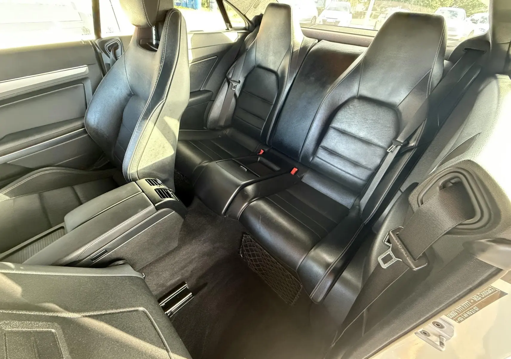 Vue intérieure arrière montrant les sièges en cuir noir d'une Mercedes Classe E 250 Coupé gris.