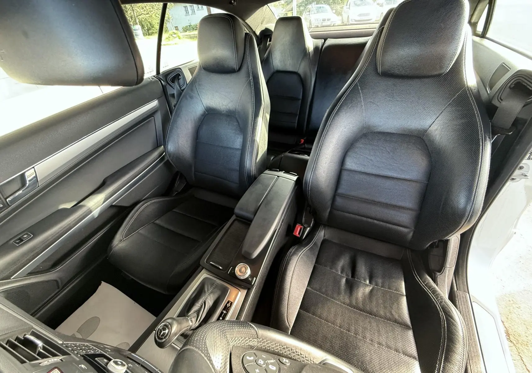 Vue intérieure de la Mercedes Classe E 250 Coupé 2011 montrant les sièges avant en cuir noir et la console centrale.