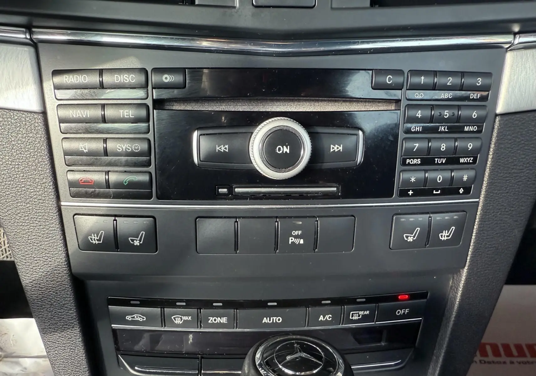 Vue rapprochée de la console centrale noire du Mercedes Classe E 250 Coupe 2.2 CDI avec commandes audio et climatisation.