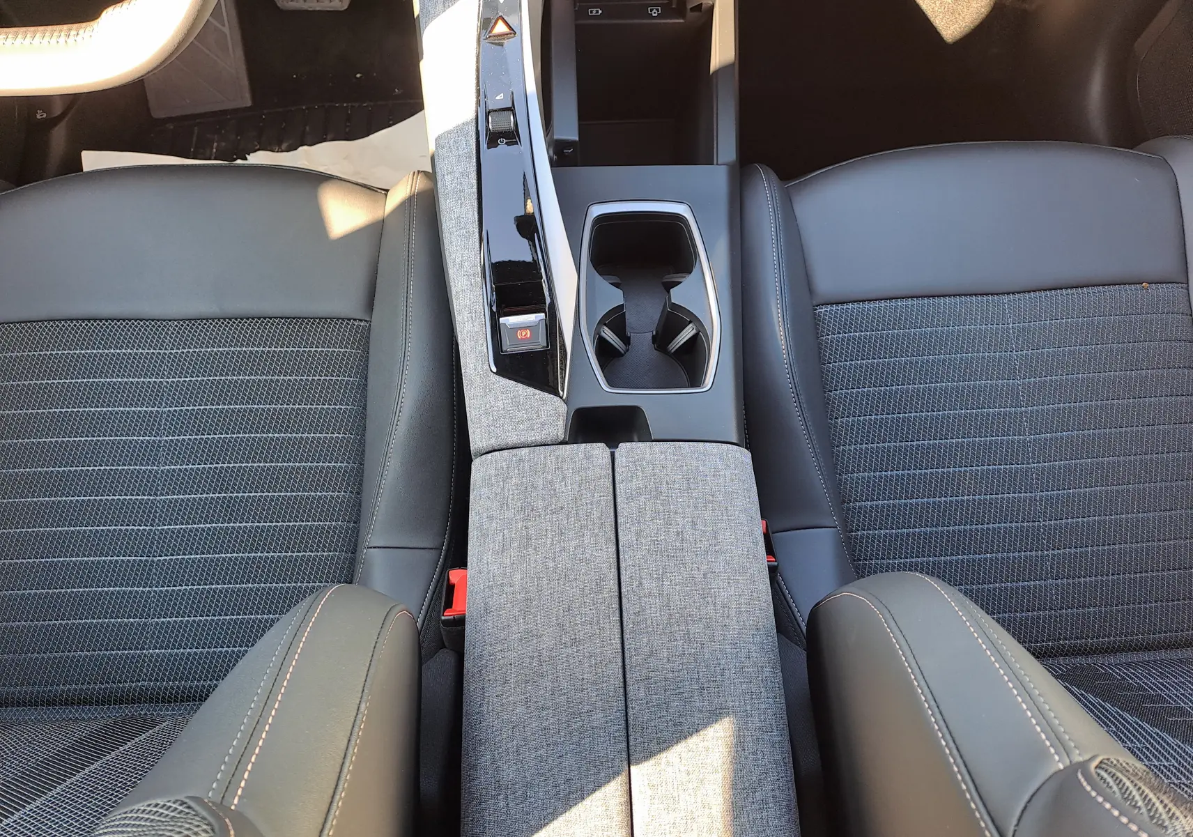 Vue plongeante sur la console centrale et les sièges gris tissu et cuir du Peugeot 3008 2024 hybride.