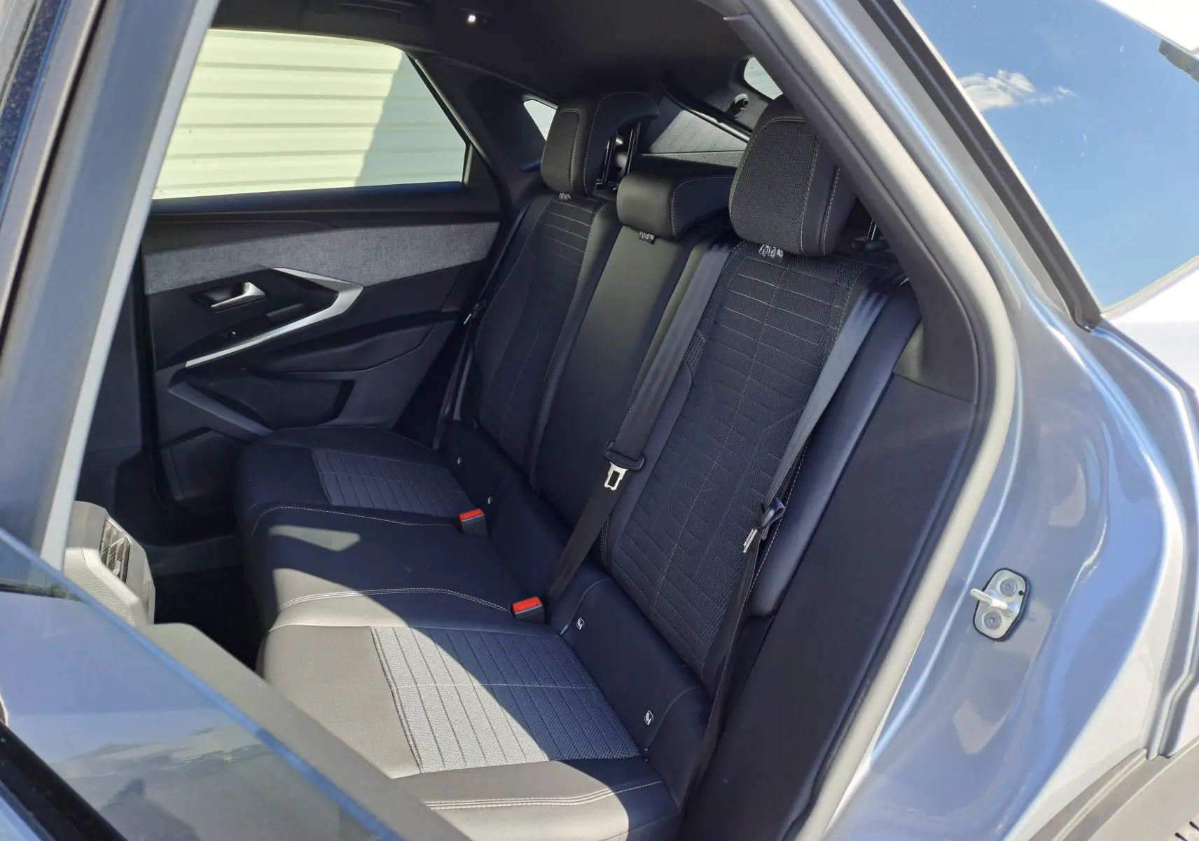 Vue intérieure côté droit des sièges arrière en tissu et cuir sur Peugeot 3008 gris Artense 2024 hybride essence.