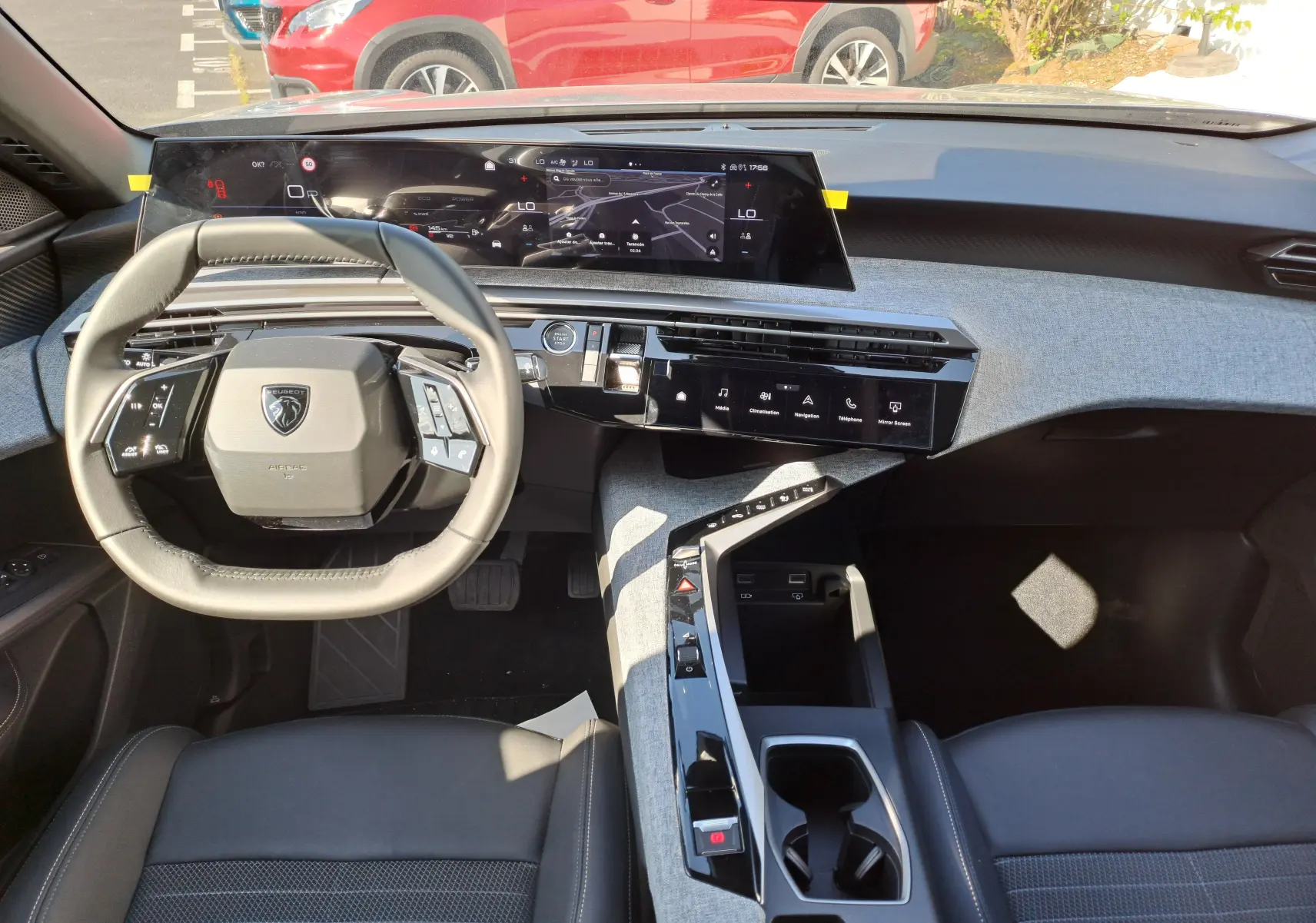 Vue intérieure avant du Peugeot 3008 2024, tableau de bord gris clair avec écran tactile panoramique et volant compact noir.