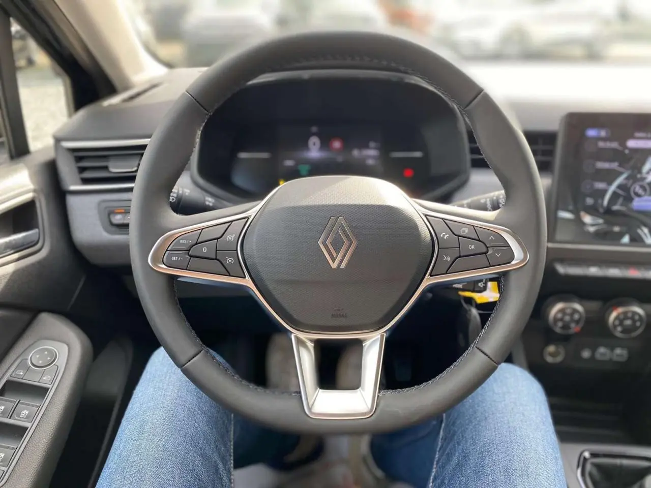 Vue rapprochée du volant Renault Clio 2025, avec commandes intégrées et tableau de bord numérique en arrière-plan.