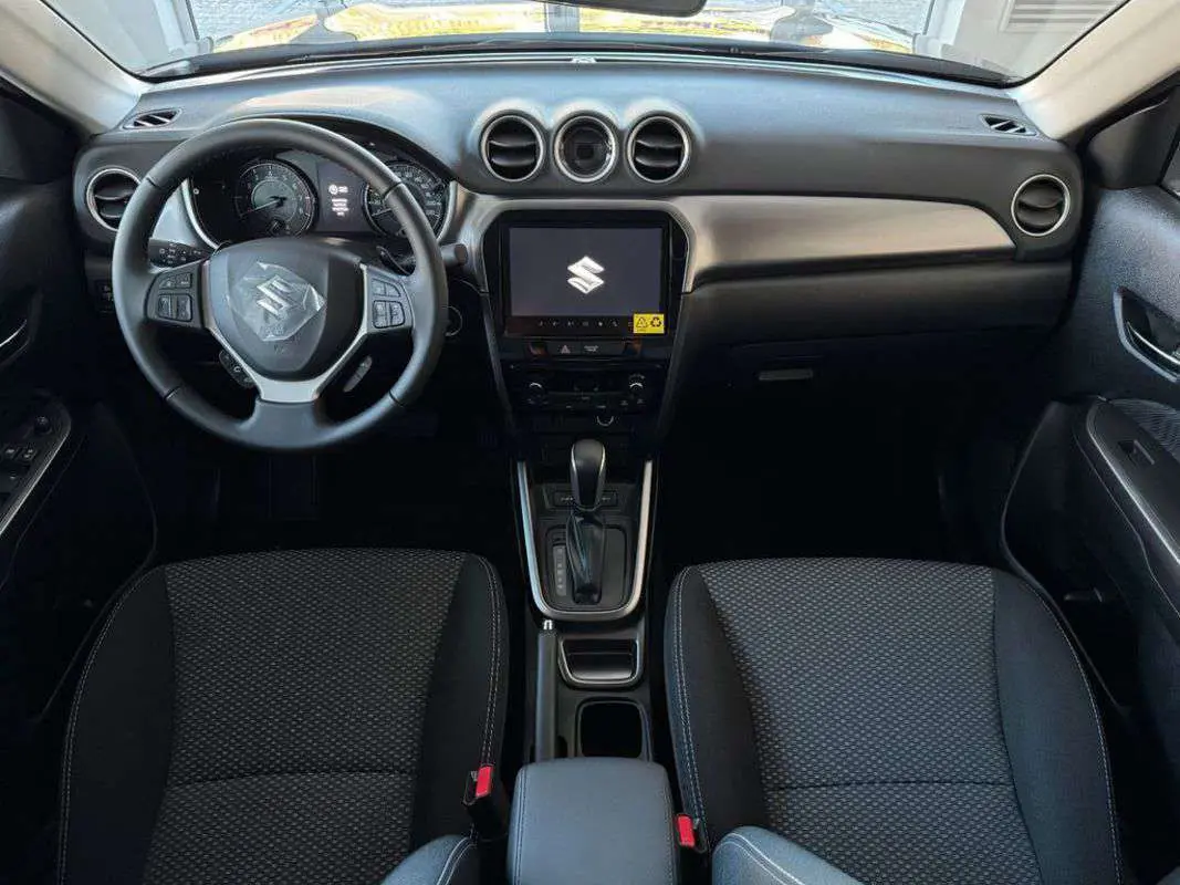 Intérieur du Suzuki Vitara 2025 en vue frontale, tableau de bord noir avec écran central tactile et volant multifonction.
