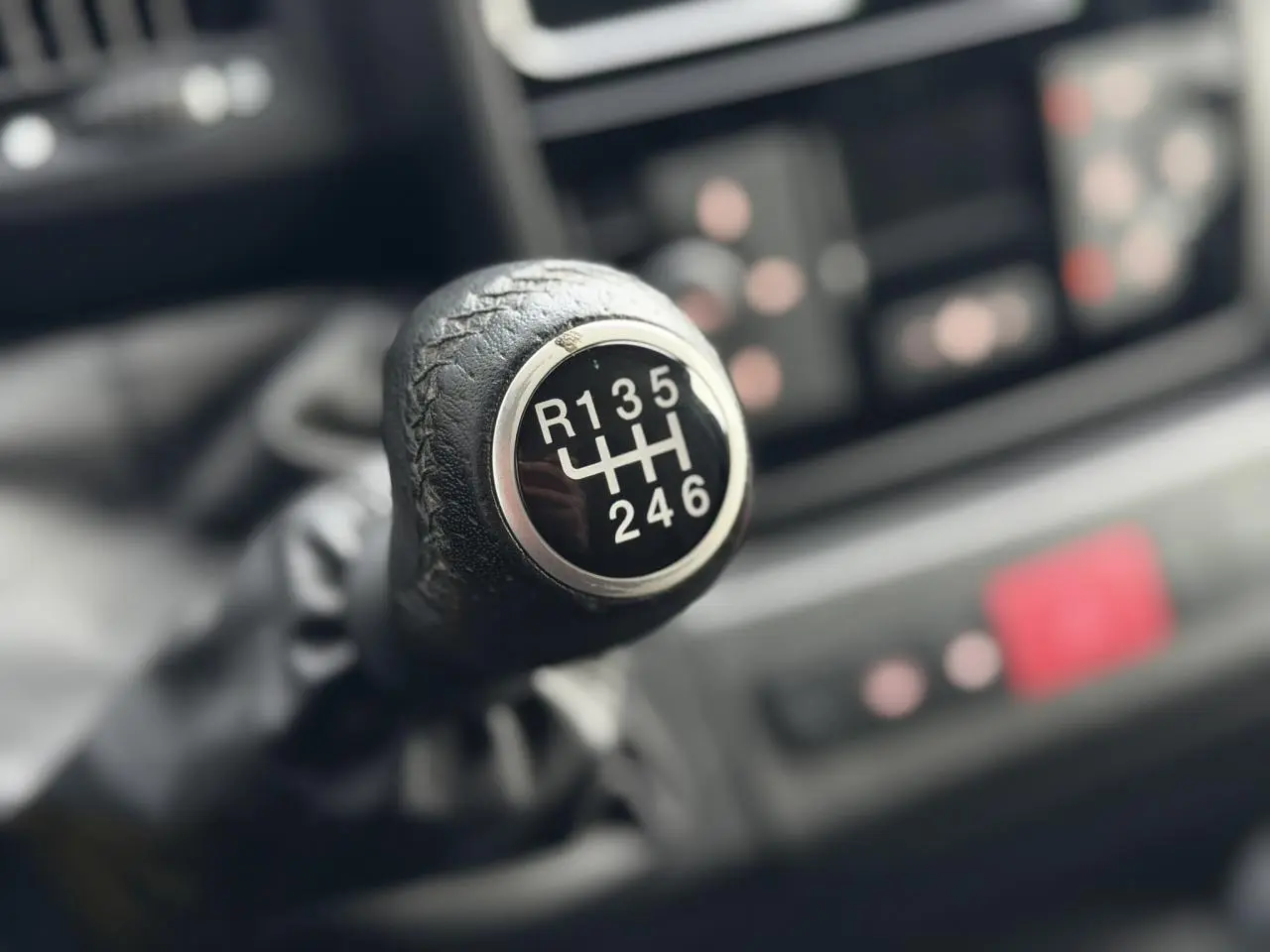 Gros plan sur le pommeau en cuir noir de la boîte manuelle 6 vitesses du fourgon Opel Movano blanc 2024.