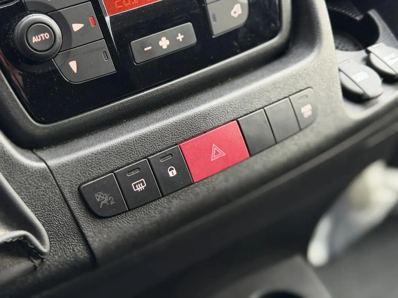 Gros plan sur les boutons de commande du tableau de bord de l'Opel Movano Fourgon blanc, avec bouton d'alerte rouge visible.