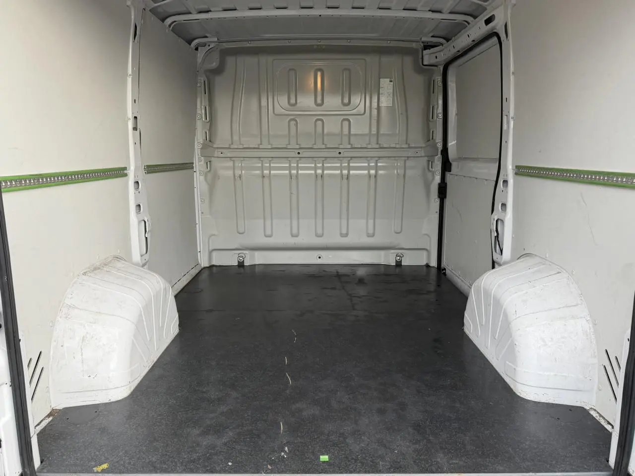 Vue intérieure arrière du fourgon blanc Opel Movano L1H1, montrant l’espace de chargement avec plancher bois noir.