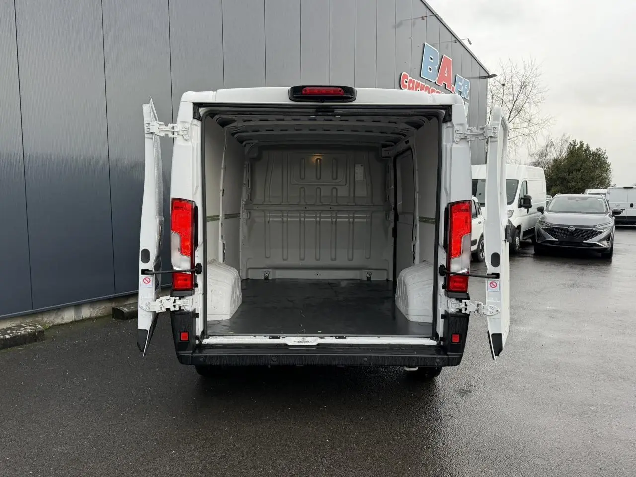Vue arrière d’un Opel Movano Fourgon blanc 2024 avec portes arrière ouvertes montrant l’espace de chargement vide.