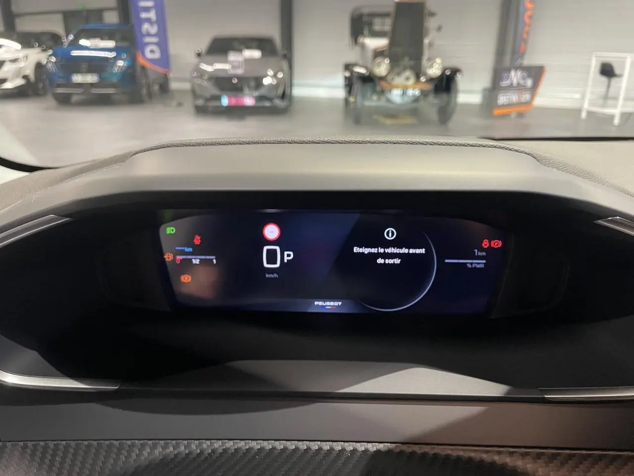 Vue rapprochée du combiné numérique Peugeot 208 1.2i Hybrid 2025 affichant le mode parking et alertes.