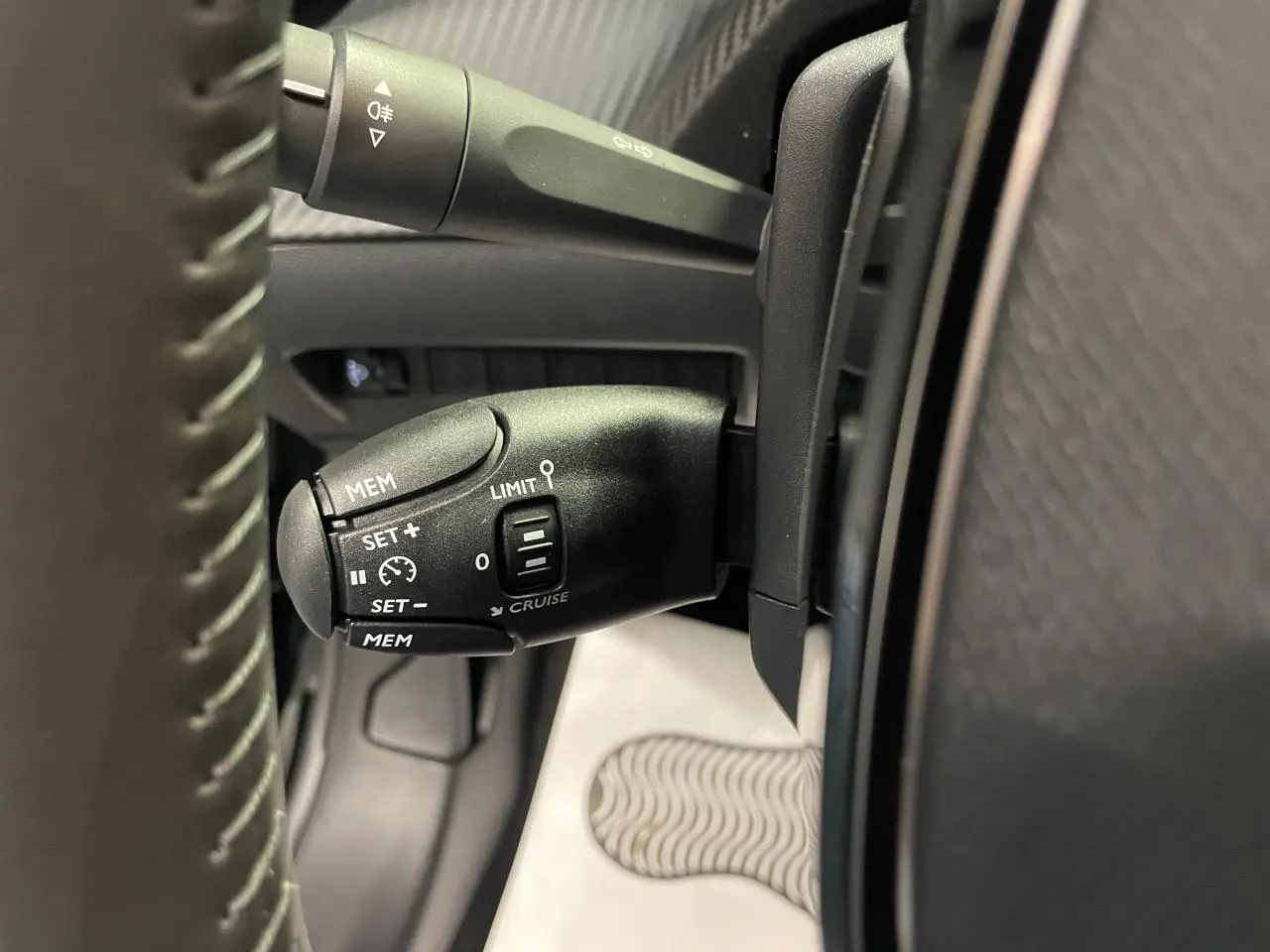 Gros plan sur la commande de régulateur de vitesse noire à gauche du volant de la Peugeot 208 2025.