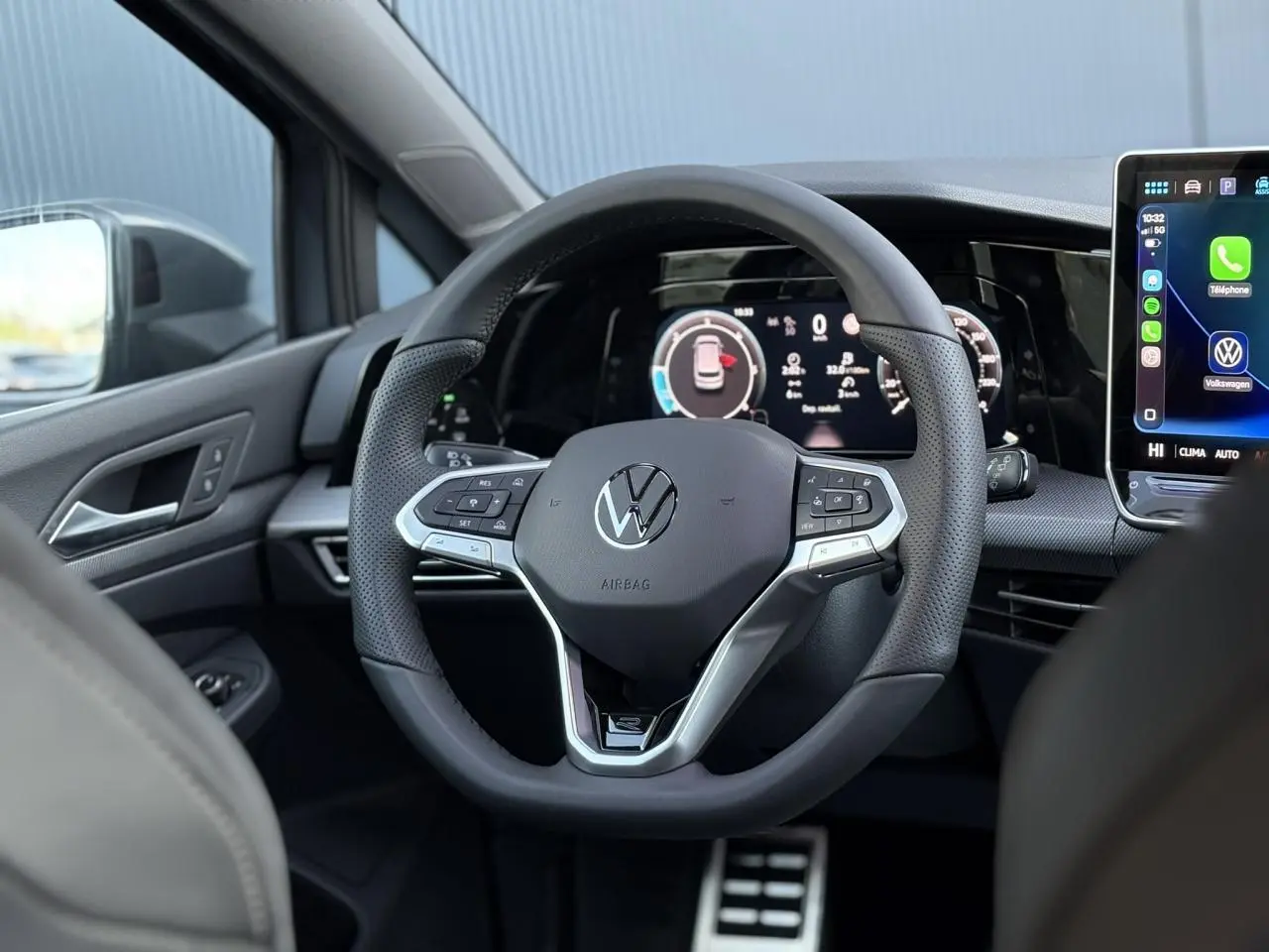 Vue intérieure centrée sur le volant multifonctions Volkswagen Golf VIII avec tableau de bord numérique et écran tactile.