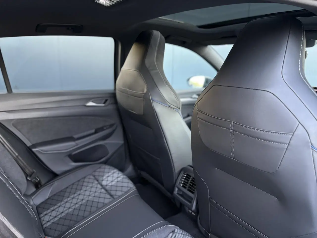Vue intérieure arrière montrant les sièges sport en cuir noir et tissu gris de la Volkswagen Golf VIII R-Line.