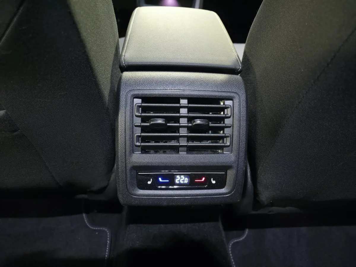 Vue rapprochée de la console arrière avec commandes climatisation et sièges chauffants, intérieur tissu noir de la Volkswagen Golf VIII rouge.