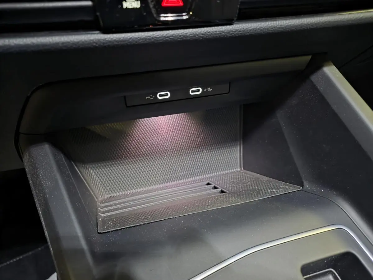 Gros plan sur la console centrale intérieure de la Volkswagen Golf VIII rouge, montrant deux ports USB-C éclairés.