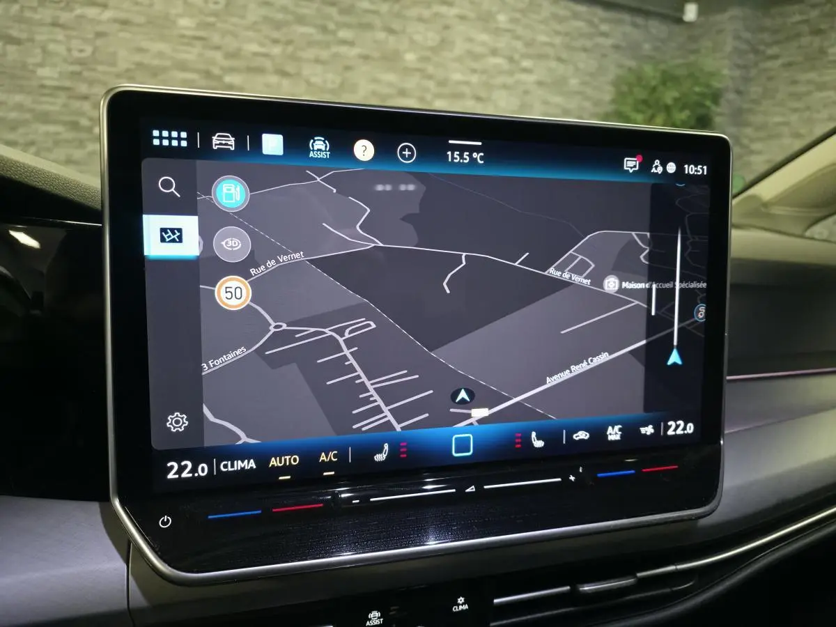 Écran tactile central du tableau de bord de la Volkswagen Golf VIII affichant la navigation et la climatisation.