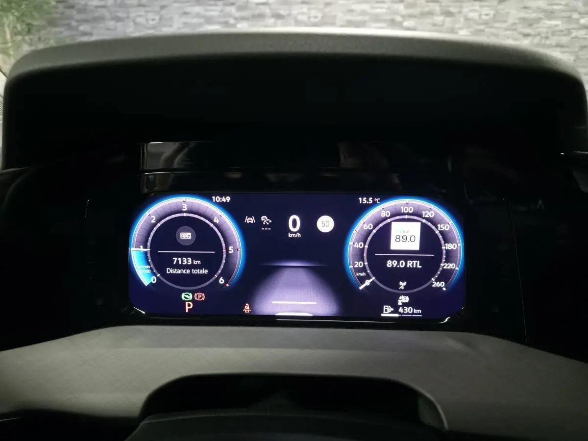 Vue rapprochée du combiné d'instruments digital bleu et noir de la Volkswagen Golf VIII rouge, affichant 7133 km.