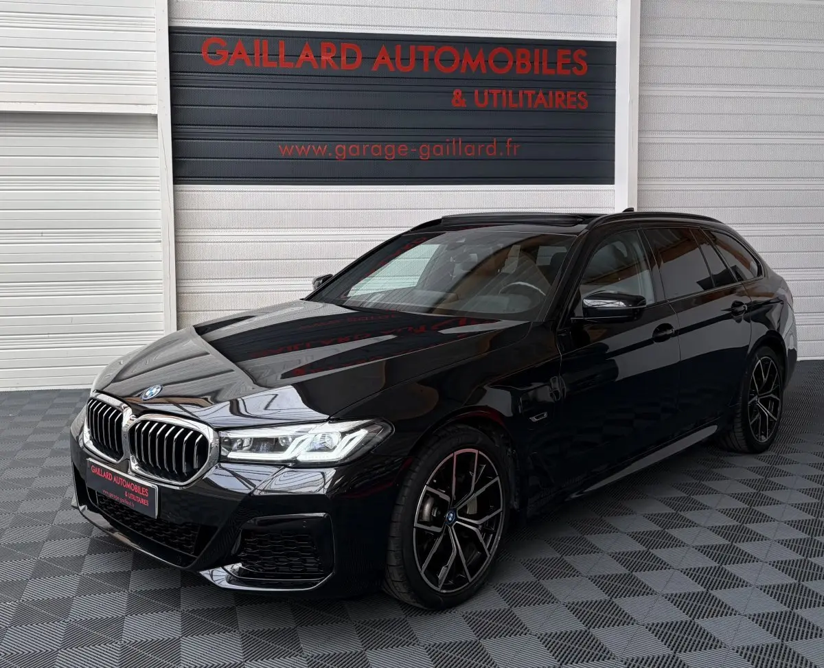 BMW Série 5 Touring 530e noir en 3/4 avant droit, avec jantes M Sport et calandre chromée distinctive.