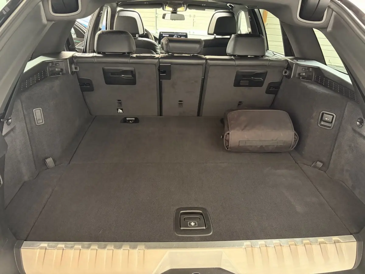 Vue intérieure du coffre spacieux de la BMW Série 5 Touring 530e noir avec banquette arrière rabattue et sac de rangement.