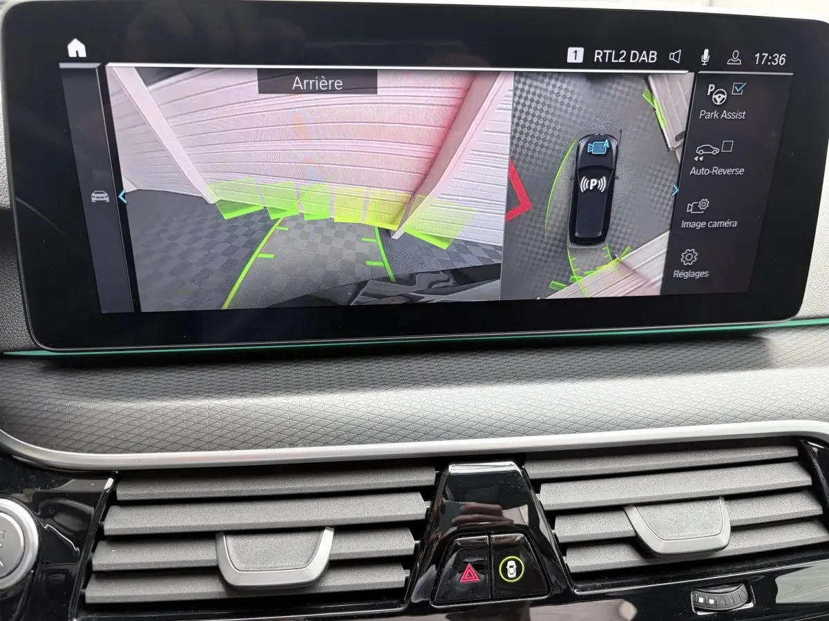 Écran tactile intérieur montrant l’aide au stationnement arrière et vue 3D du BMW Série 5 Touring noir 2023.