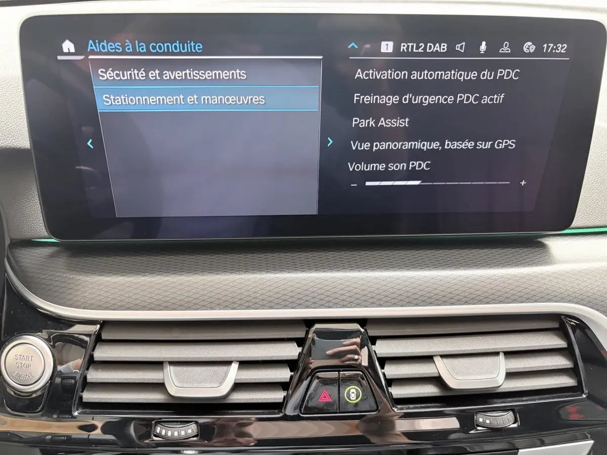 Vue rapprochée du tableau de bord noir de la BMW Série 5 Touring 530e 2023, affichant l'écran tactile des aides au stationnement.