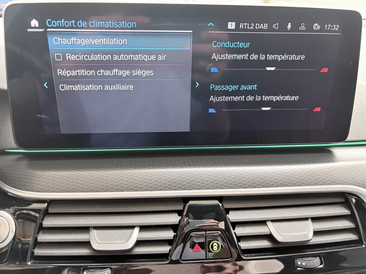 Écran tactile central affichant les réglages de climatisation dans l'habitacle d'une BMW Série 5 Touring noire.