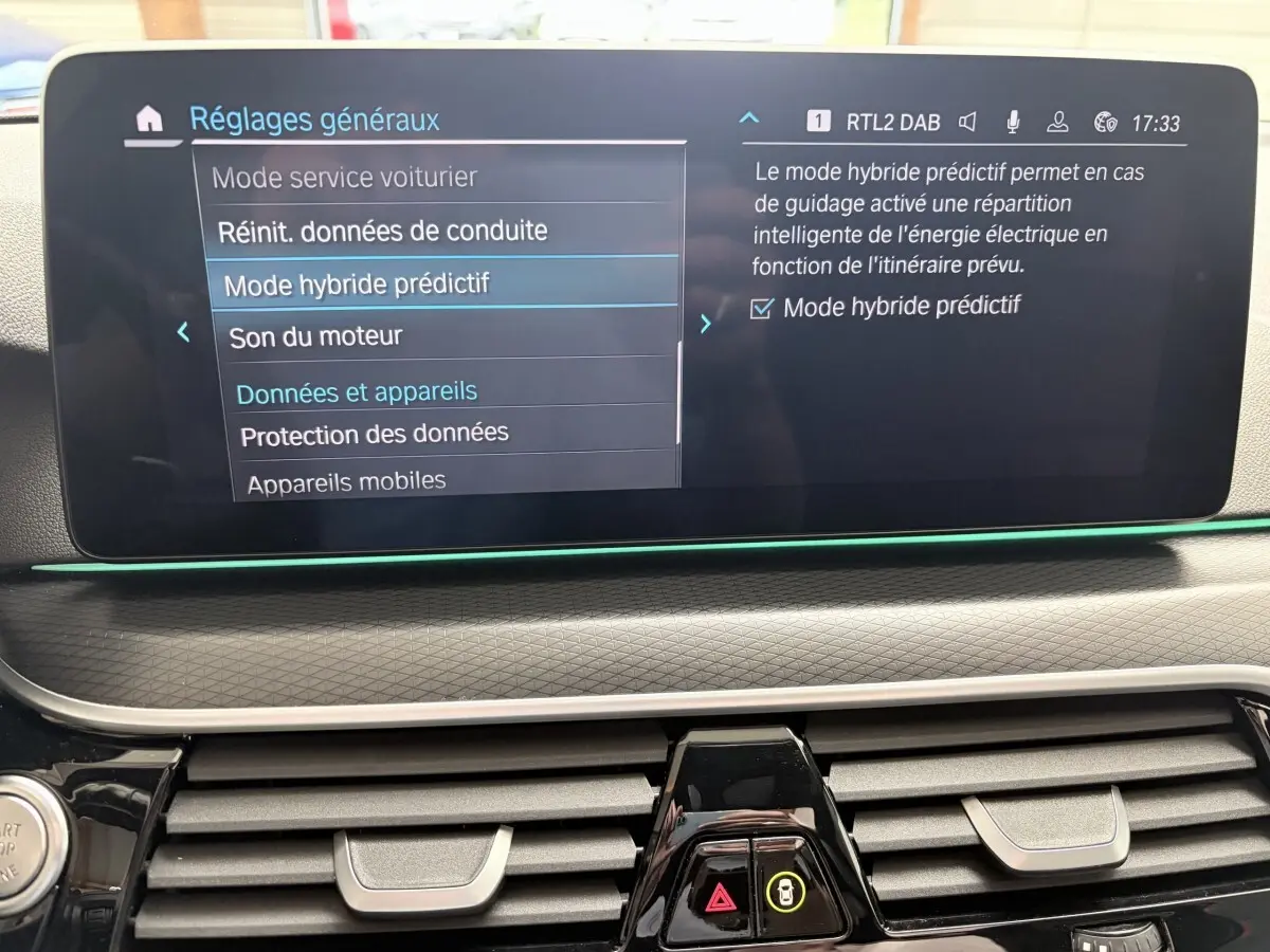 Écran tactile central affichant les réglages du mode hybride prédictif dans l'habitacle d'une BMW Série 5 Touring noire.