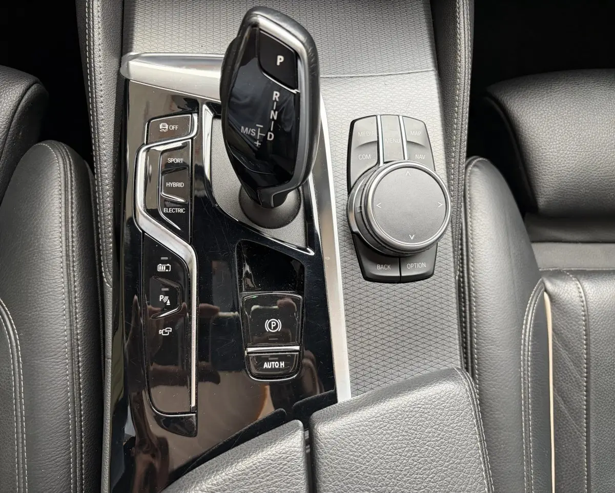 Gros plan sur la console centrale noire de la BMW Série 5 Touring 530e avec levier de vitesses et molette de contrôle.