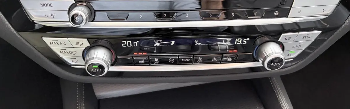 Gros plan sur la console centrale noire de la BMW Série 5 Touring 530e, affichant la climatisation automatique bi-zone.