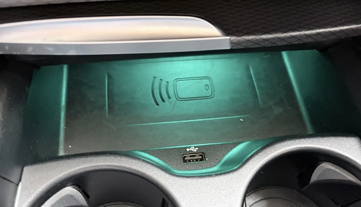 Gros plan sur la console centrale noire de la BMW Série 5 Touring 530e avec chargeur sans fil et port USB visible.