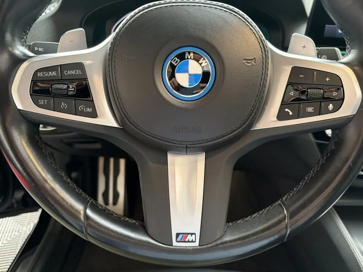 Gros plan sur le volant cuir noir avec logo BMW et badge M Sport de la BMW Série 5 Touring 530e 2023.