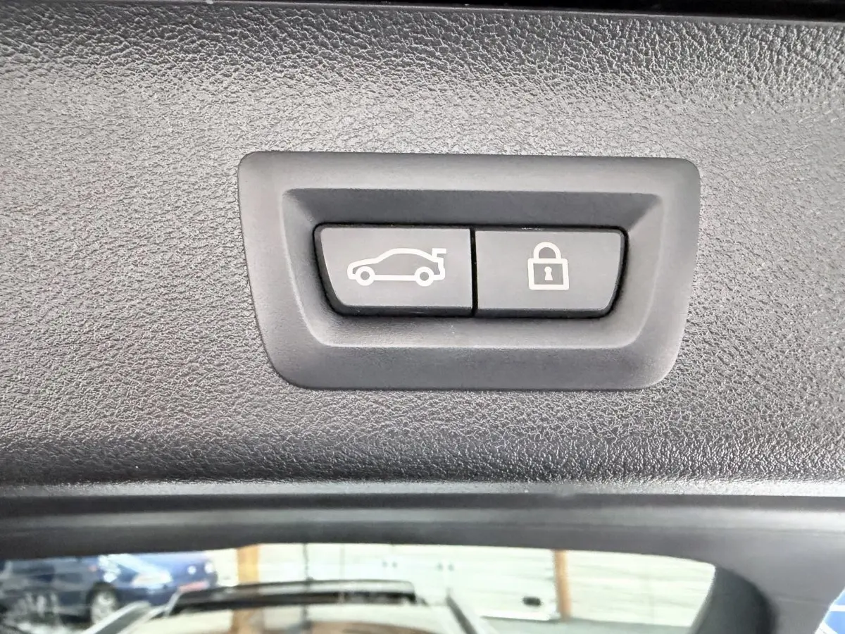 Boutons d'ouverture et de verrouillage du coffre sur le hayon intérieur d'une BMW Série 5 Touring noire 2023.