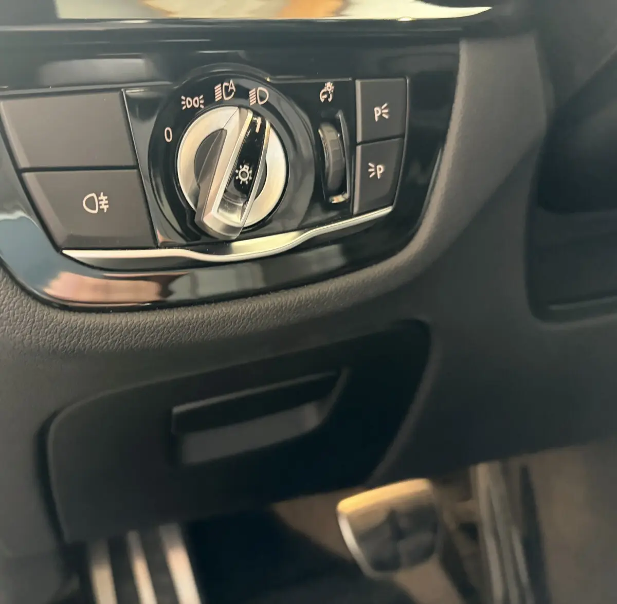Gros plan sur la commande des phares noire et chromée dans l’habitacle d’une BMW Série 5 Touring 530e noire.