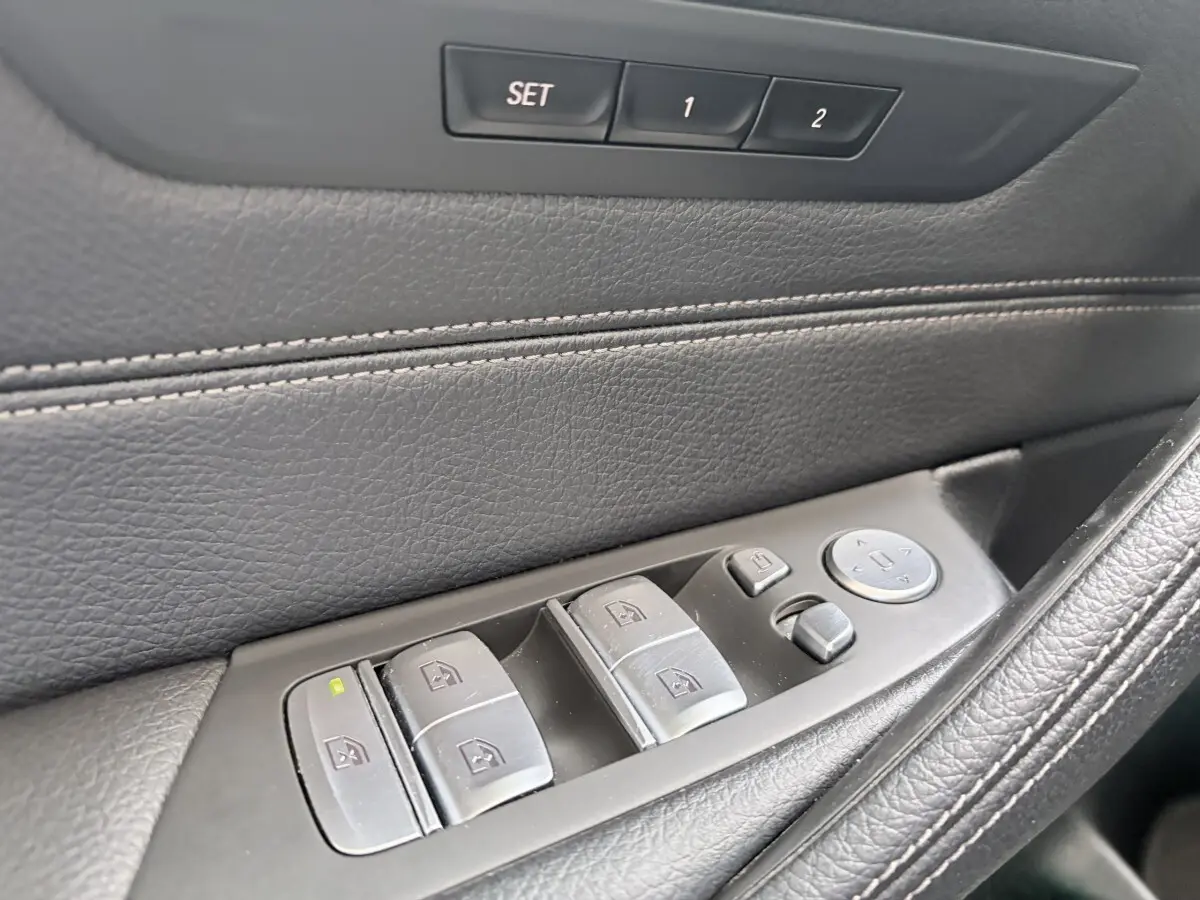 Gros plan sur la commande des vitres côté conducteur en cuir noir de la BMW Série 5 Touring 530e M Sport 2023.