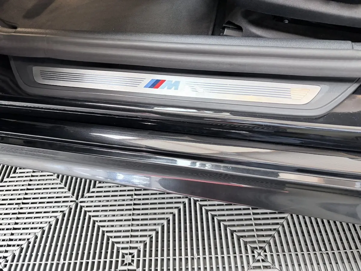 Gros plan sur la plaque de seuil de porte M Sport côté gauche d'une BMW Série 5 Touring noire 2023.