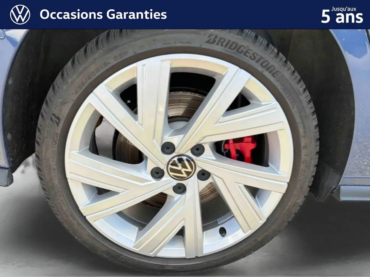 Gros plan sur la jante alliage 17'' Richmond argentée avec étrier de frein rouge d’une Volkswagen Golf 1.5 eHybrid bleue.