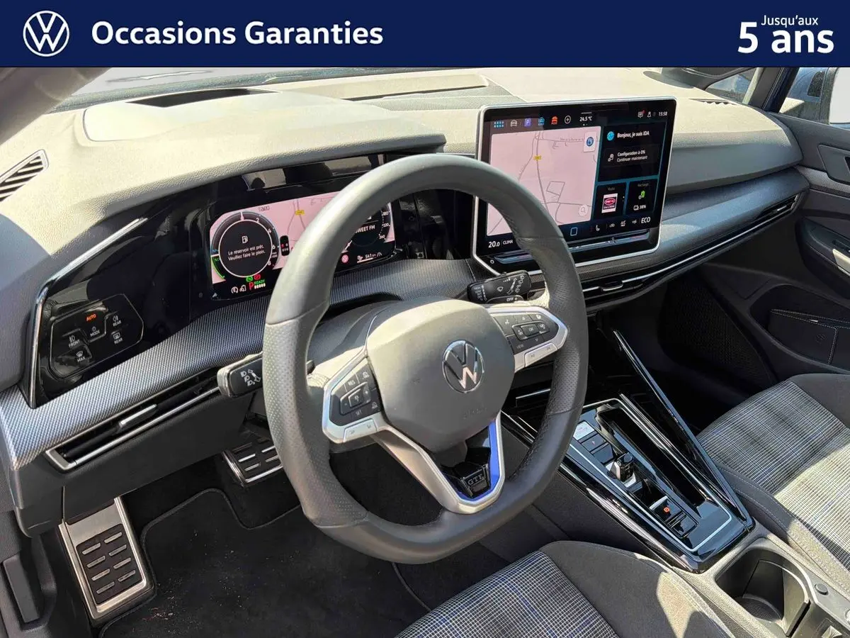 Vue intérieure du poste de conduite de la Volkswagen Golf 1.5 eHybrid 2025, volant sport cuir et écran tactile central visible.