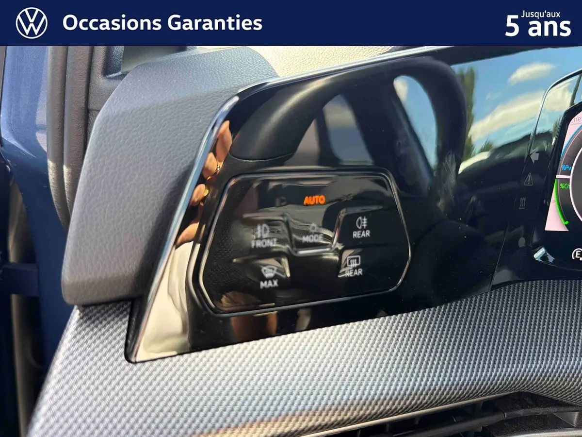 Détail du tableau de bord côté gauche de la Volkswagen Golf 1.5 eHybrid 2025 bleu, avec commandes d’éclairage et finition texturée.