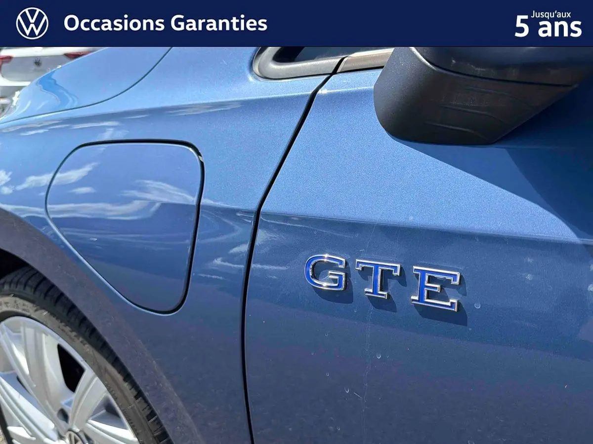 Détail côté gauche arrière d’une Volkswagen Golf 1.5 eHybrid bleue avec badge GTE et trappe de recharge visible.