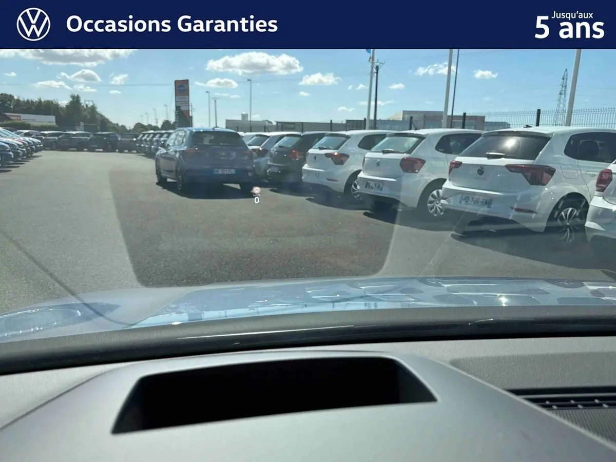 Vue avant depuis l'habitacle d'une Volkswagen Golf bleue 2025 avec affichage tête haute visible sur le pare-brise.