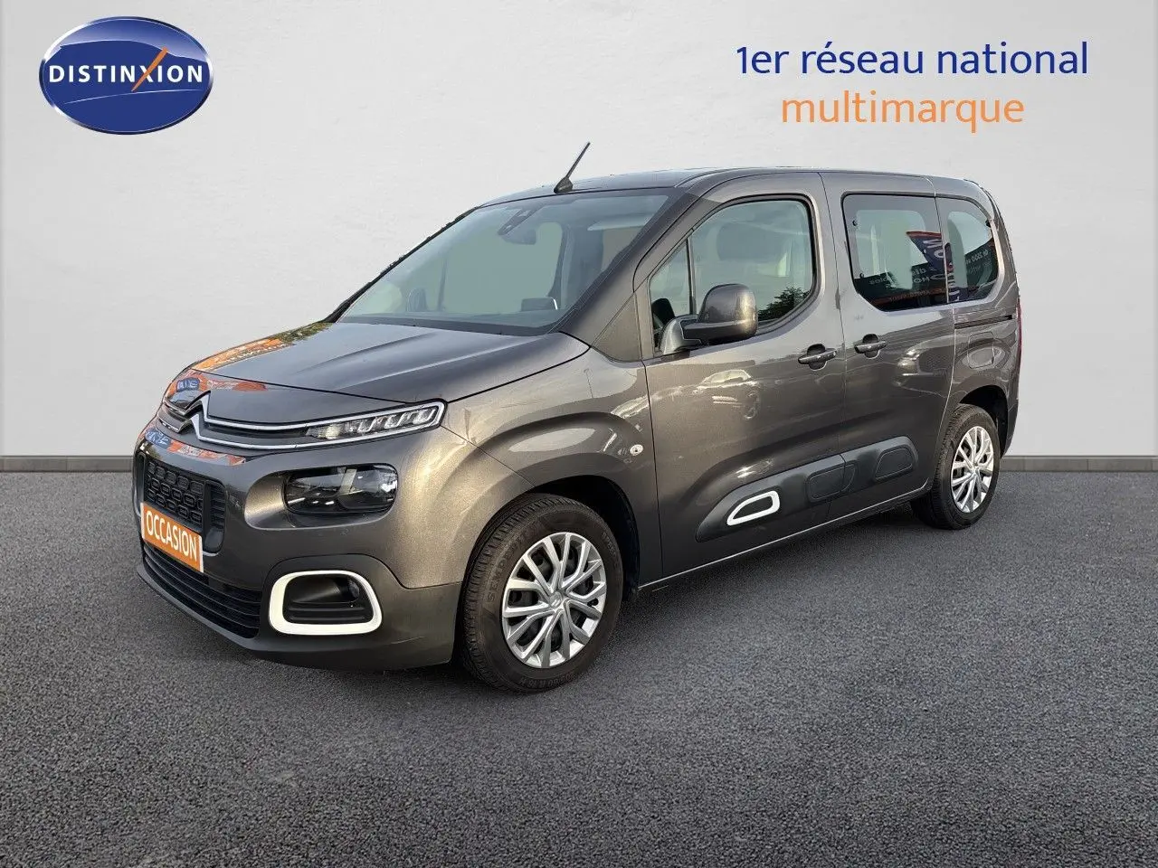Vue 3/4 avant droit d'un Citroën Berlingo Multispace gris platinium avec protections latérales blanches et jantes alliage.