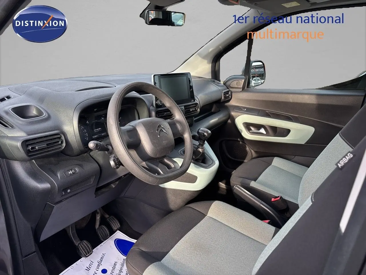 Vue intérieure côté conducteur du Citroën Berlingo Multispace gris platinium, avec tableau de bord et sièges bicolores.