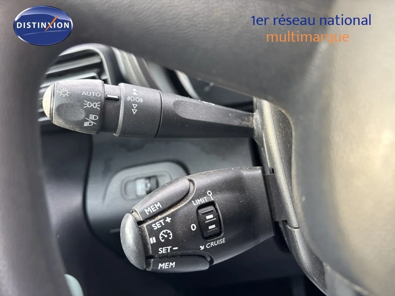 Gros plan sur les commandes au volant du Citroën Berlingo Multispace gris platinium, montrant les leviers de clignotants et régulateur de vitesse.